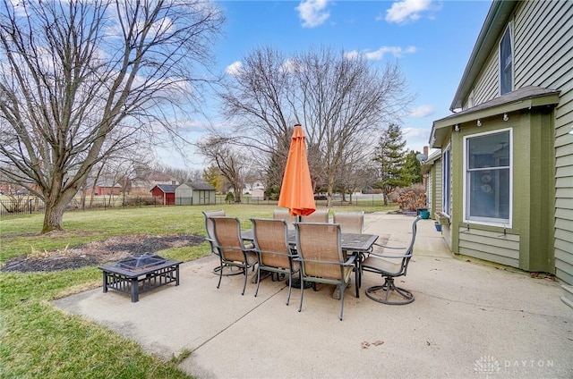 view of patio / terrace featuring an outdoor fire pit, a fenced backyard, an outdoor structure, a shed, and outdoor dining space