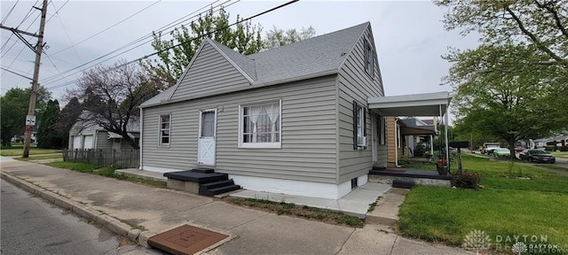 view of front of house with a shingled roof and a front lawn