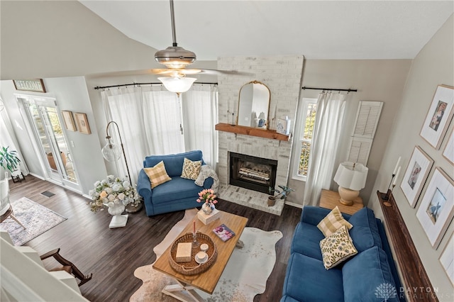 living area with baseboards, a ceiling fan, lofted ceiling, wood finished floors, and a fireplace