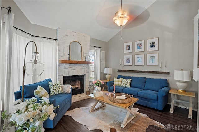 living area featuring lofted ceiling, a brick fireplace, baseboards, and wood finished floors