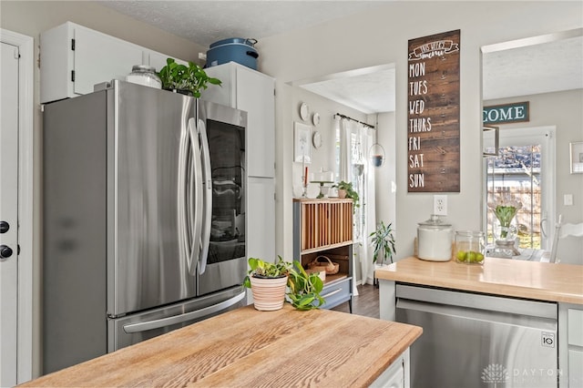 kitchen with white cabinets, stainless steel appliances, and a textured ceiling