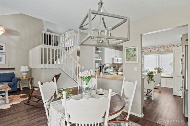 dining space with baseboards, dark wood finished floors, an inviting chandelier, and stairs