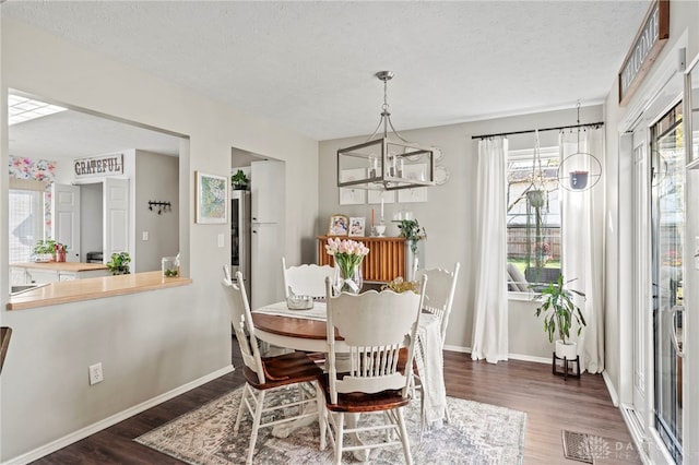 dining area with an inviting chandelier, a textured ceiling, baseboards, and wood finished floors