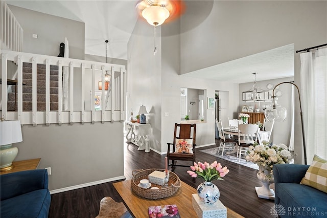 living area featuring baseboards, stairway, a chandelier, and wood finished floors