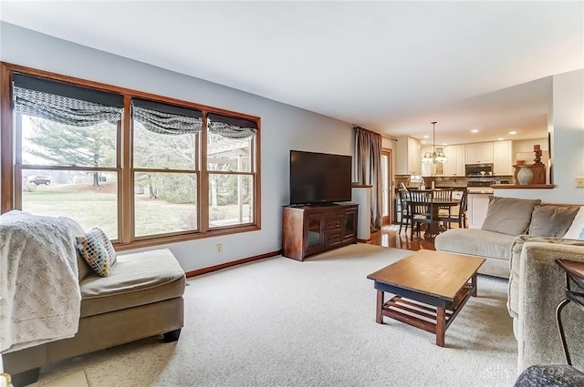 living area with baseboards and light colored carpet