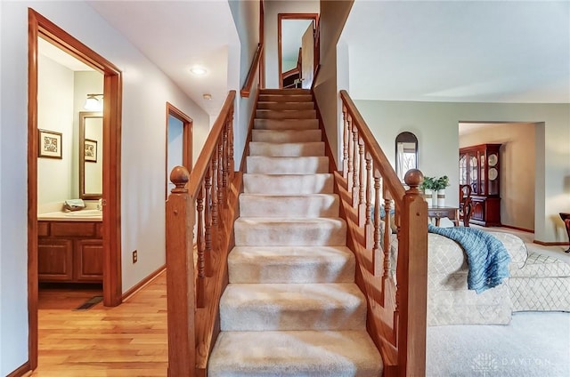 staircase featuring baseboards, wood finished floors, and recessed lighting