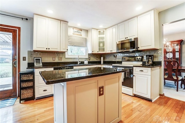 kitchen featuring white cabinetry, electric range, stainless steel microwave, and a sink