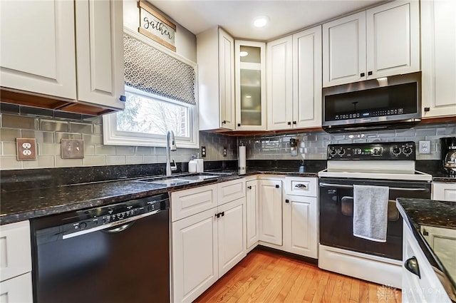 kitchen featuring black dishwasher, stainless steel microwave, white cabinets, a sink, and range with electric cooktop