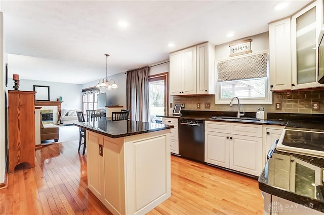 kitchen featuring dishwasher, tasteful backsplash, a sink, and light wood-style floors