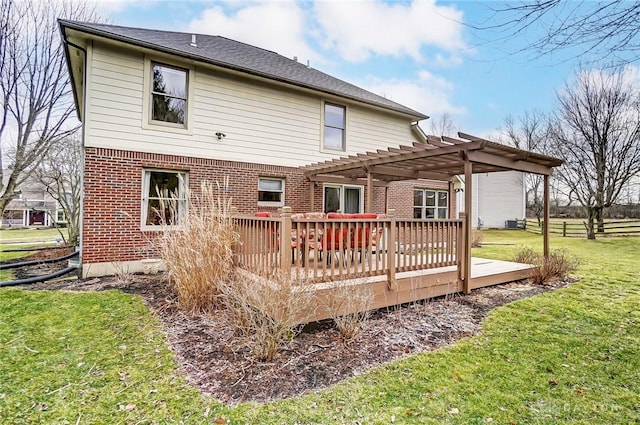 back of property with a deck, brick siding, fence, a yard, and a pergola