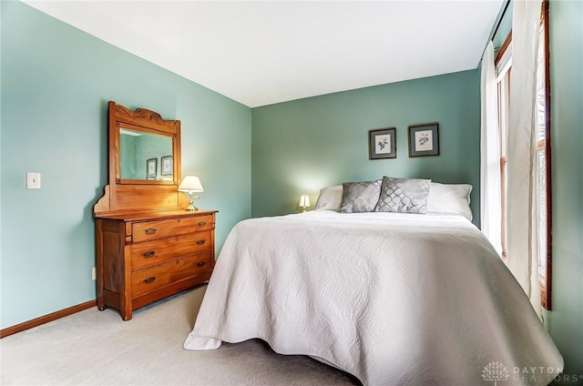 carpeted bedroom featuring multiple windows and baseboards