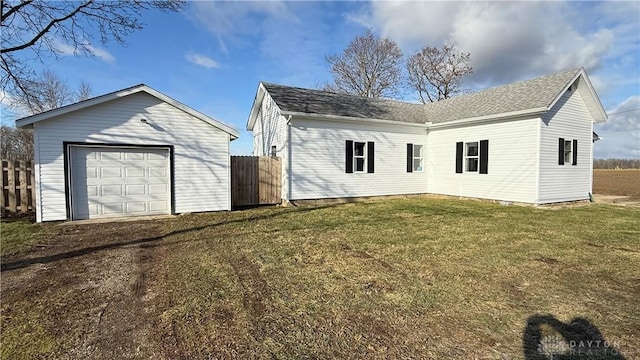 exterior space with a detached garage, an outdoor structure, fence, a yard, and driveway