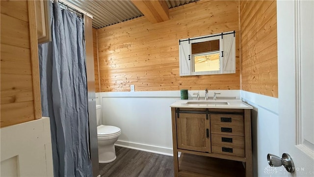 full bathroom featuring toilet, wood walls, wood finished floors, vanity, and beamed ceiling