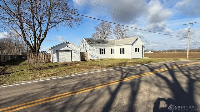 view of front of house with an outbuilding, a detached garage, a front yard, fence, and driveway