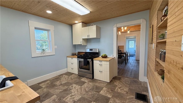 kitchen featuring stainless steel range with gas cooktop, visible vents, a healthy amount of sunlight, white cabinetry, and wooden ceiling