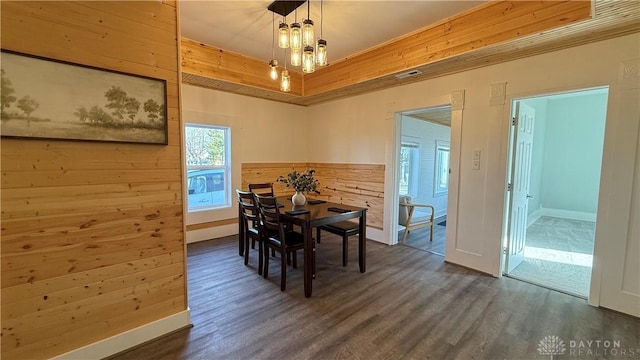 dining area featuring dark wood-style floors, a notable chandelier, visible vents, and wooden walls