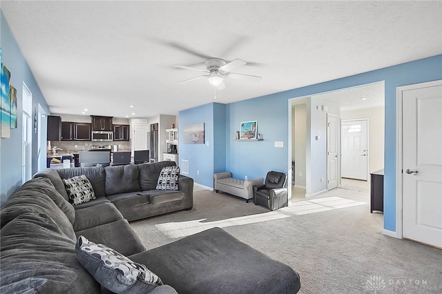 living room featuring a textured ceiling, recessed lighting, light carpet, a ceiling fan, and baseboards