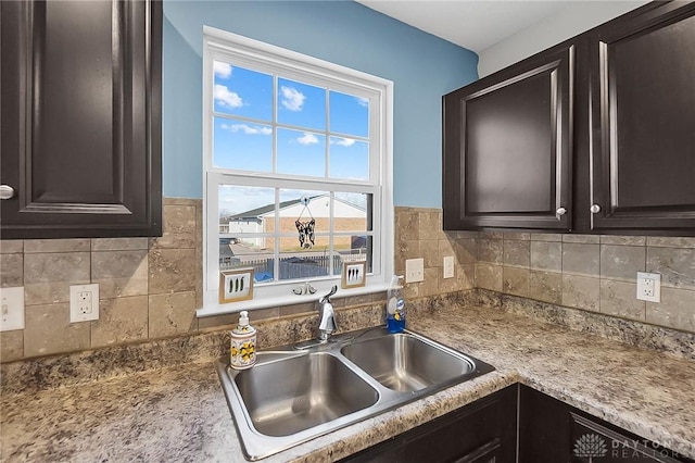 kitchen featuring a sink, backsplash, and dark brown cabinetry