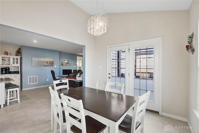 dining room with a towering ceiling, baseboards, visible vents, and a notable chandelier