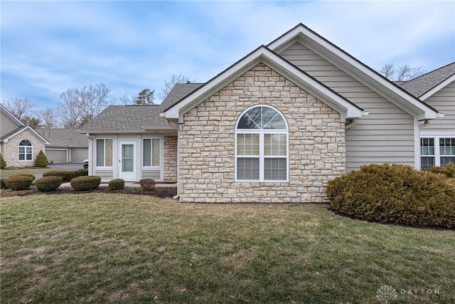 view of front of house featuring a shingled roof and a front yard