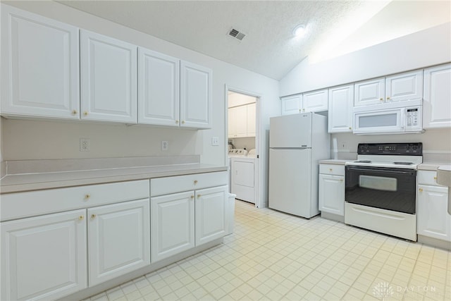 kitchen with lofted ceiling, light countertops, visible vents, washing machine and dryer, and white appliances