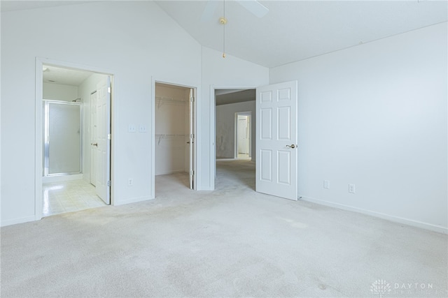 unfurnished bedroom with carpet floors, a closet, a spacious closet, ensuite bathroom, and high vaulted ceiling