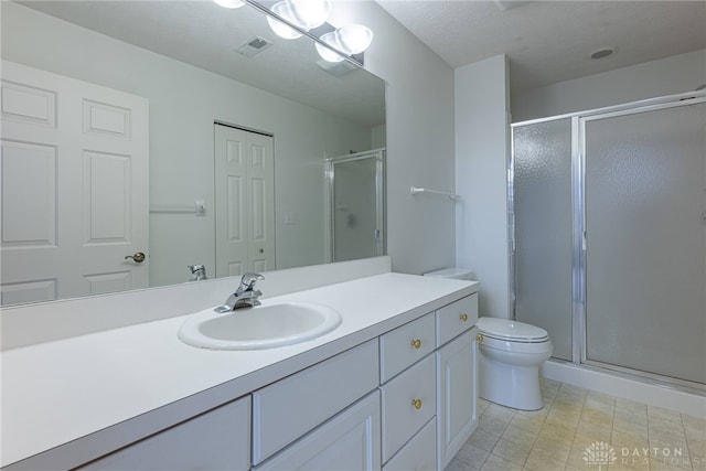 bathroom featuring a textured ceiling, toilet, vanity, visible vents, and a shower stall