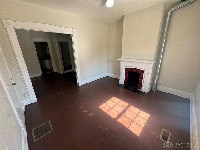 unfurnished living room featuring visible vents, a fireplace, baseboards, and hardwood / wood-style flooring