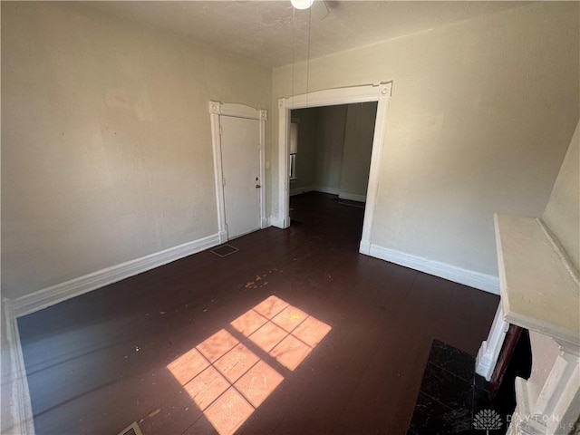 spare room featuring wood finished floors, visible vents, and baseboards