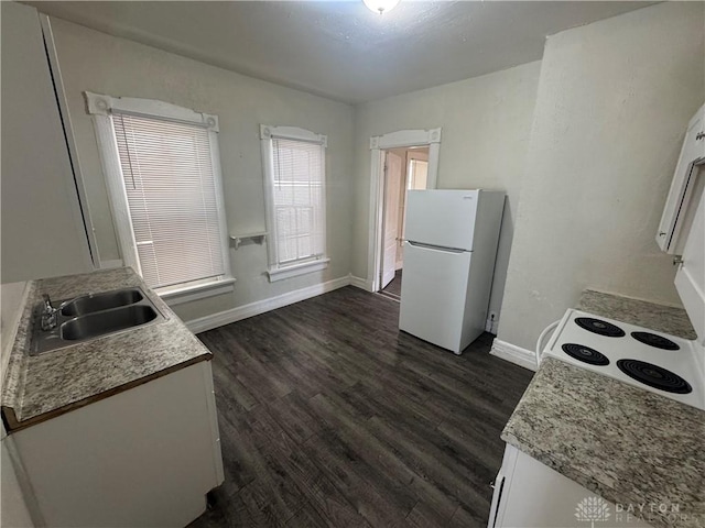 kitchen with a sink, white cabinetry, light countertops, freestanding refrigerator, and dark wood finished floors