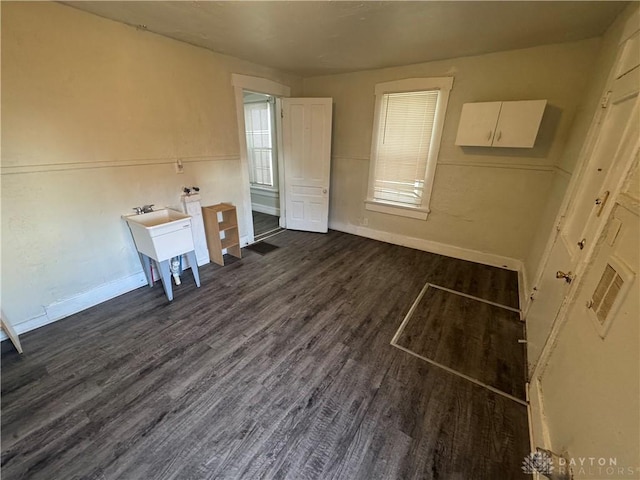 interior space featuring dark wood-type flooring, multiple windows, a sink, and baseboards