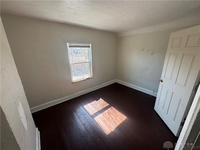 unfurnished bedroom with a textured ceiling, hardwood / wood-style flooring, and baseboards