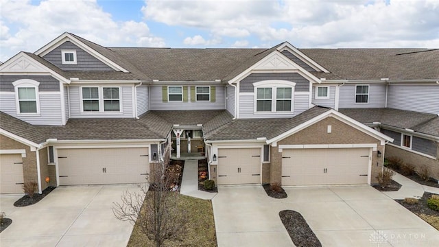 view of property featuring a garage, concrete driveway, brick siding, and roof with shingles