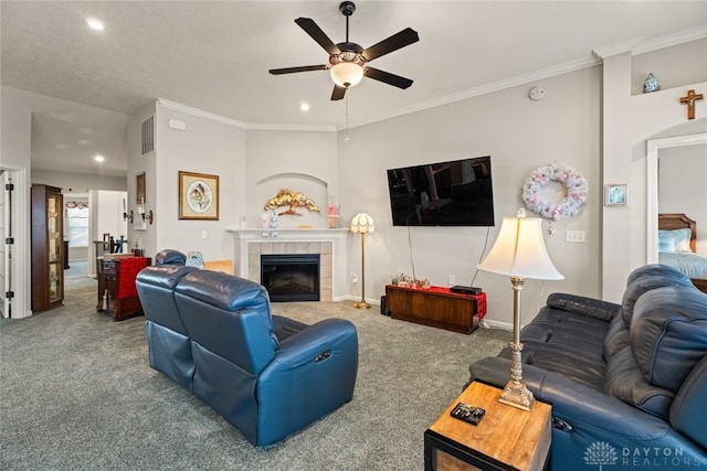 carpeted living area with ceiling fan, a fireplace, visible vents, and crown molding