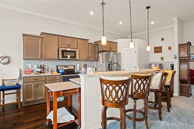 kitchen featuring appliances with stainless steel finishes, ornamental molding, an island with sink, and decorative backsplash