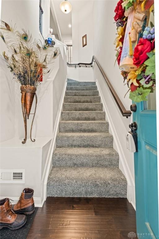 stairs featuring wood finished floors and visible vents