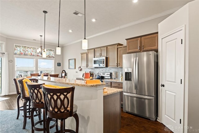 kitchen with stainless steel appliances, tasteful backsplash, a kitchen island with sink, and crown molding