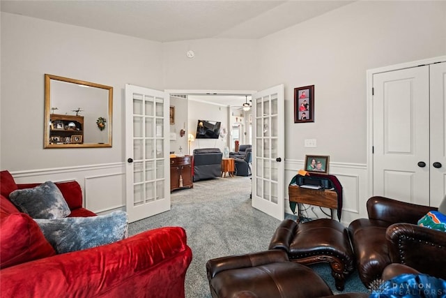 living area featuring wainscoting, a decorative wall, carpet flooring, and french doors