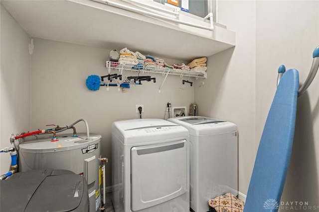 washroom featuring laundry area, electric water heater, and washer and clothes dryer