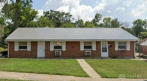 ranch-style home featuring brick siding, metal roof, and a front yard