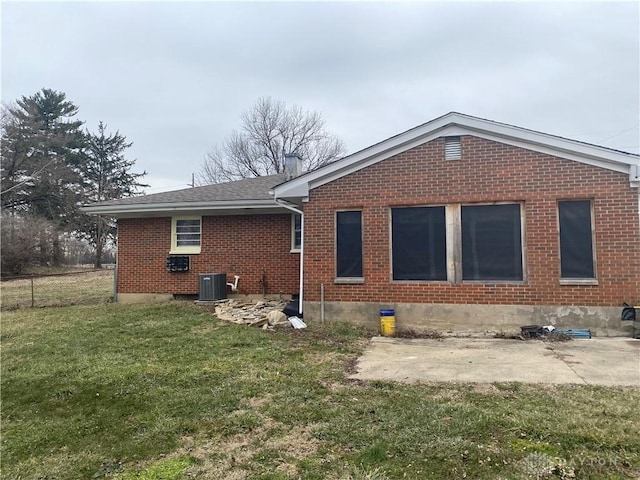 back of house featuring brick siding, a lawn, a shingled roof, and central air condition unit