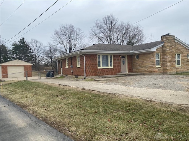 ranch-style home with an outbuilding, brick siding, a chimney, a front yard, and driveway