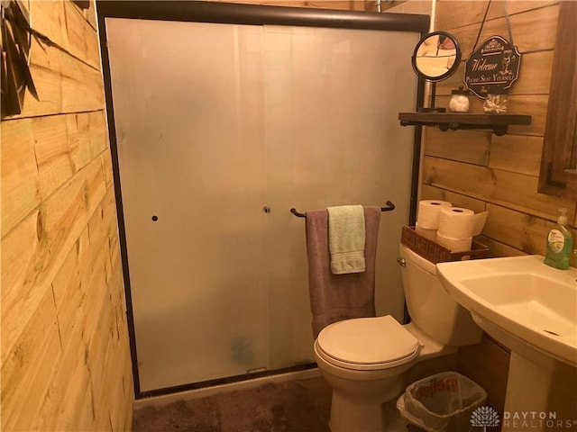 bathroom with a shower stall, wooden walls, and toilet