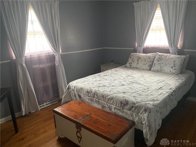 bedroom with baseboard heating and wood finished floors