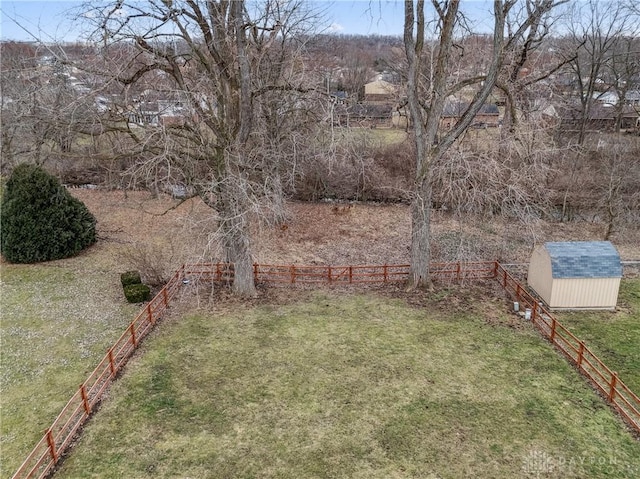 view of yard featuring a storage unit, fence, and an outbuilding