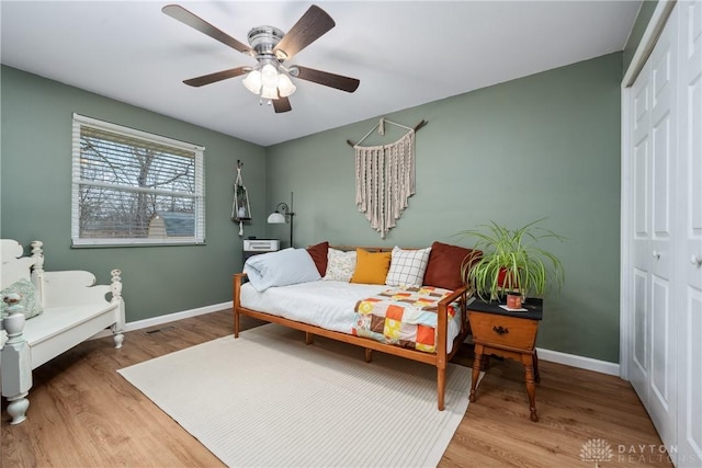 bedroom featuring a closet, ceiling fan, baseboards, and wood finished floors