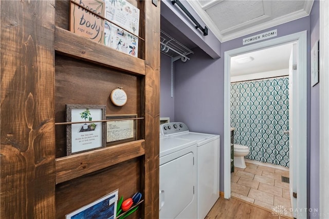 laundry room featuring crown molding, a textured ceiling, wood finished floors, washer and dryer, and laundry area