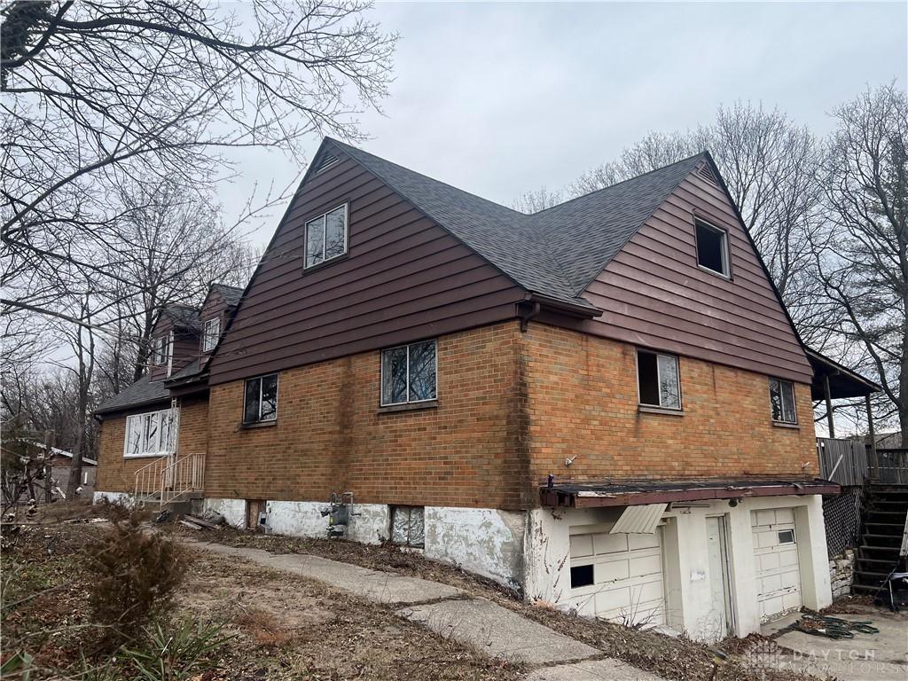 view of side of property featuring brick siding, roof with shingles, and an attached garage