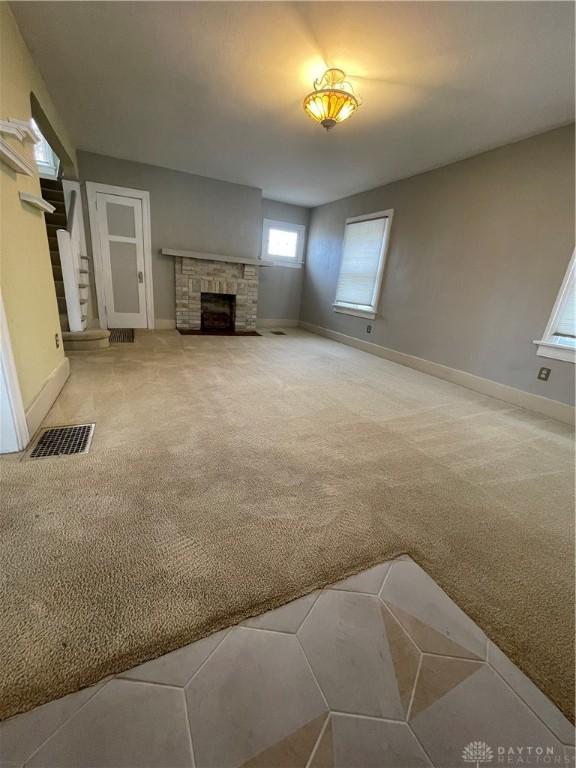 50 Woodcrest Ave, Dayton, OH 45405 - unfurnished living room with carpet floors, a stone fireplace, baseboards, and visible vents