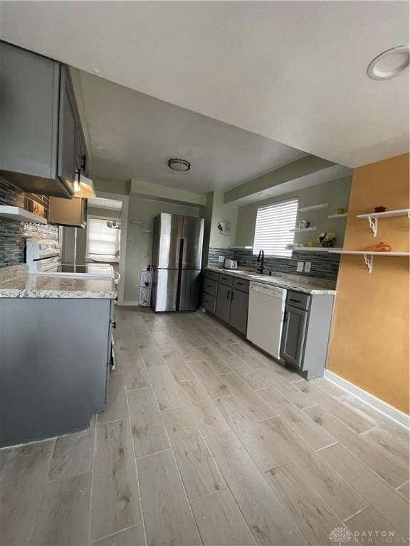 50 Woodcrest Ave, Dayton, OH 45405 - kitchen featuring freestanding refrigerator, white dishwasher, gray cabinetry, and decorative backsplash